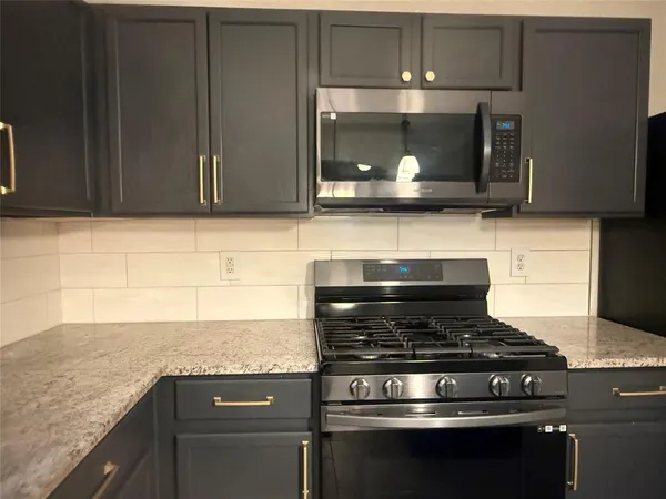 a kitchen with granite countertop a stove and a microwave