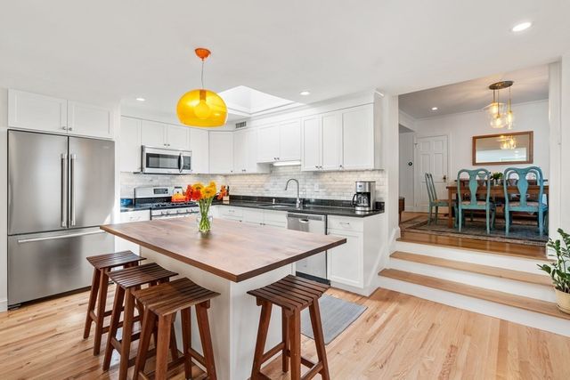 a kitchen with stainless steel appliances granite countertop a table chairs and a refrigerator