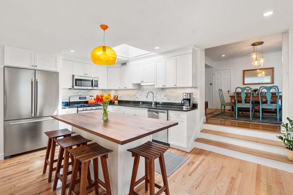 a kitchen with stainless steel appliances granite countertop a table chairs and a refrigerator