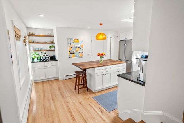 a kitchen with stainless steel appliances granite countertop a refrigerator a sink a stove and white cabinets with wooden floor