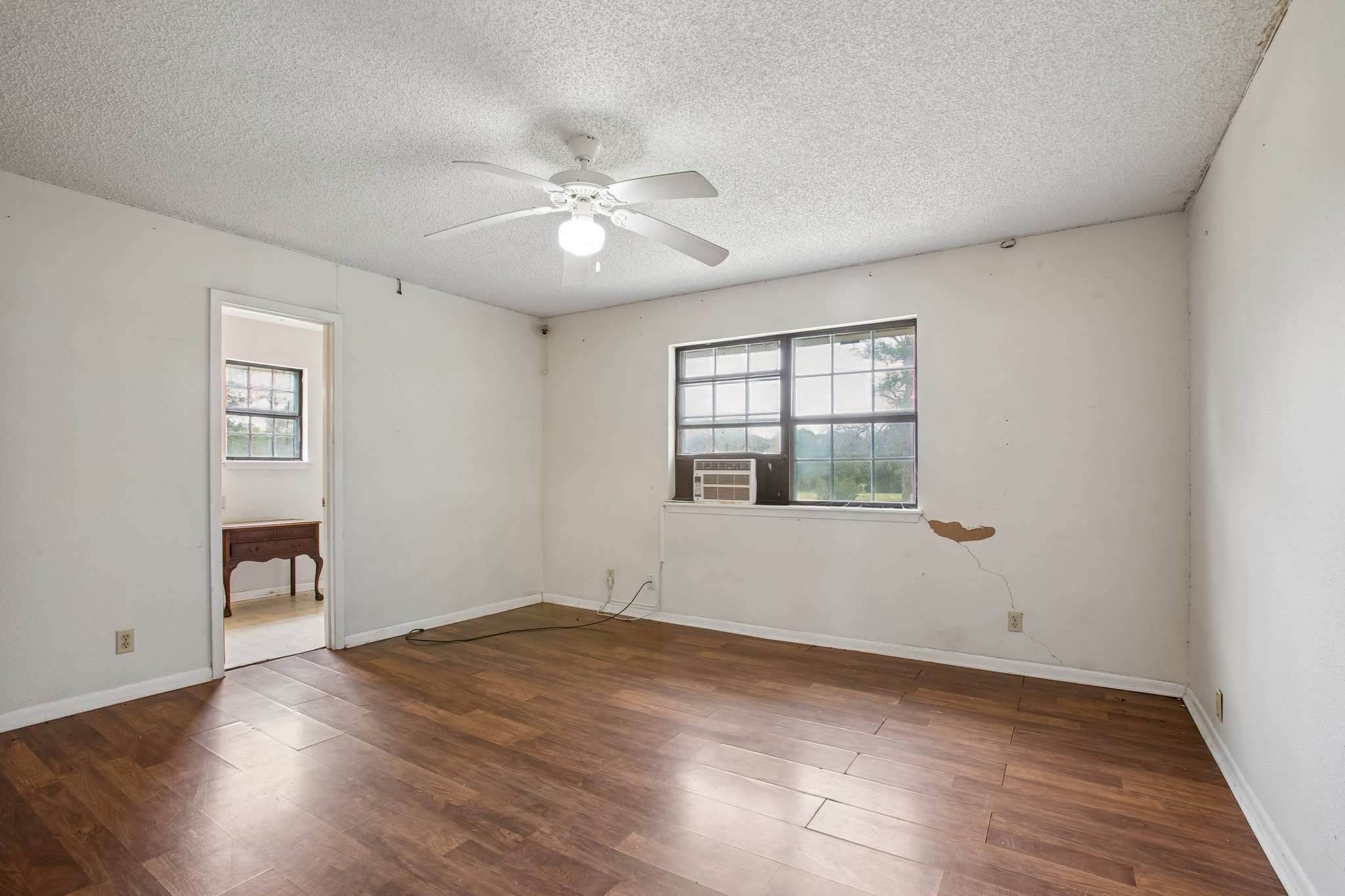 406 Monkey Road Elgin, TX 78621 - Photo 13 of 39 Spacious room featuring wood-finish flooring, a ceiling fan with integrated lighting, a window-mounted air conditioning unit, and a textured white ceiling