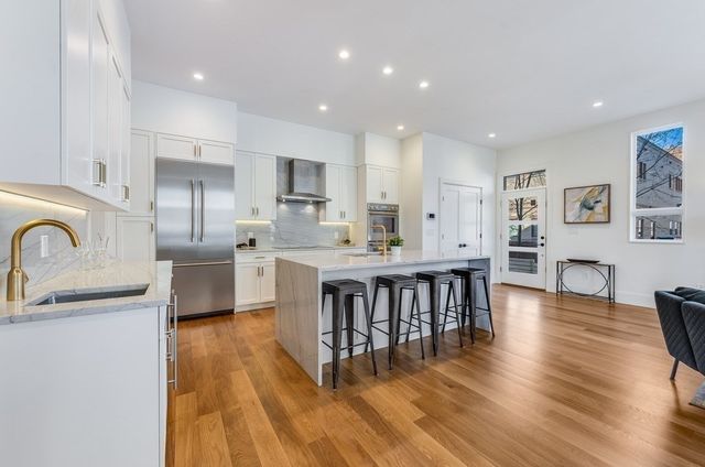 a kitchen with stainless steel appliances granite countertop a dining table chairs stove microwave and cabinets