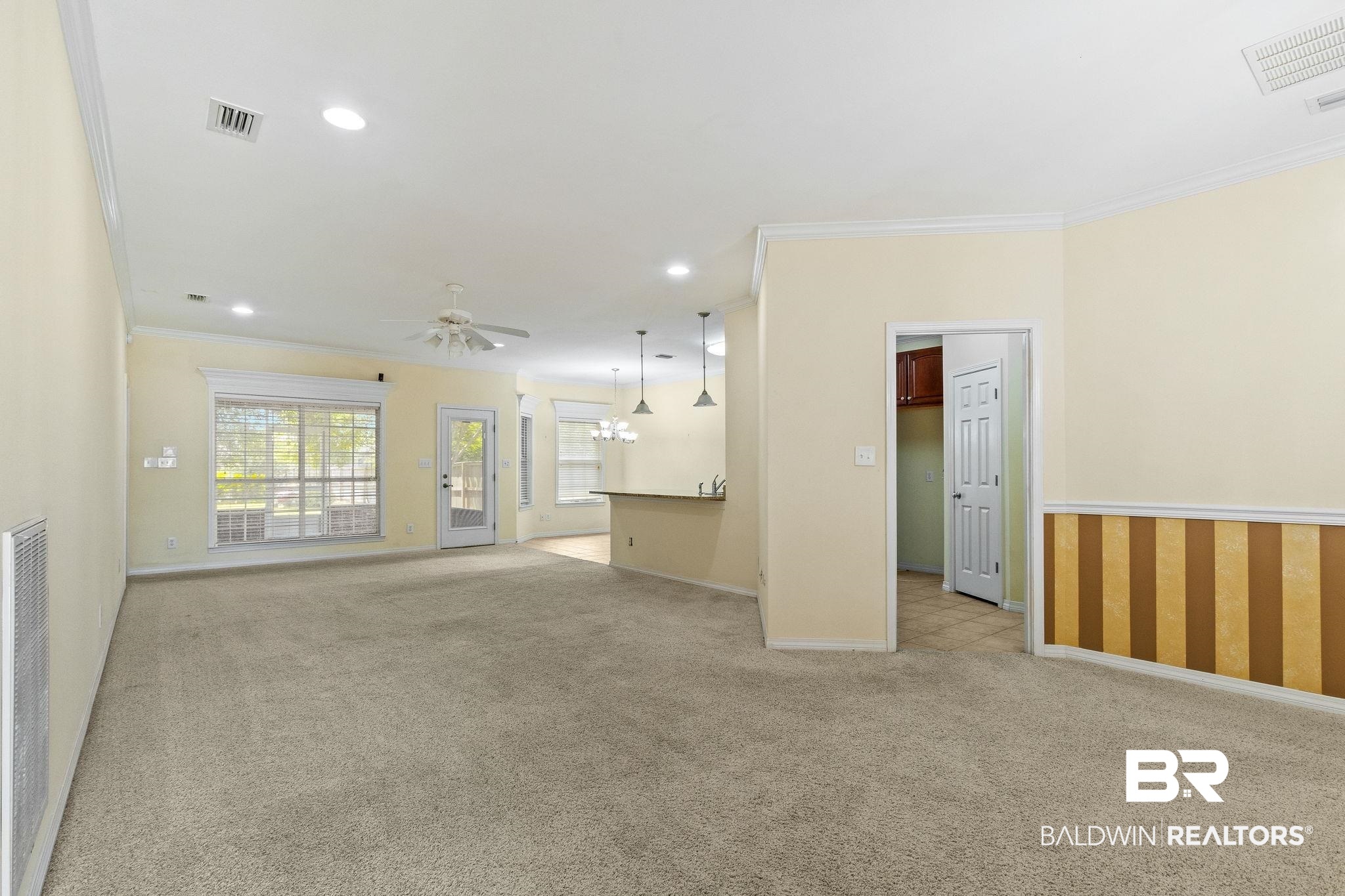 166 Club Drive Fairhope, AL 36532 - Photo 7 of 41 Unfurnished living room featuring crown molding, ceiling fan with notable chandelier, and light colored carpet