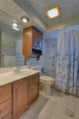 a bathroom with a granite countertop sink a toilet and a shower