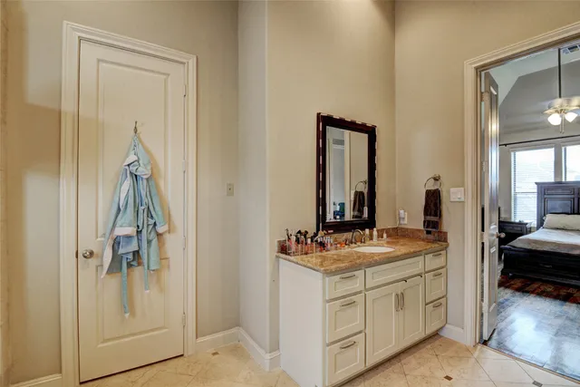 a en suite bathroom with a granite countertop sink and a mirror