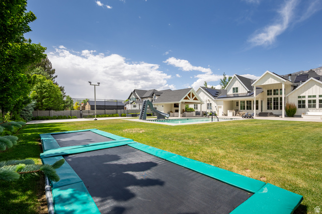 630 East Center Street Alpine, UT 84004 - Photo 98 of 115 Expansive rear yard featuring a manicured lawn, inground trampolines, and a dedicated sports court with a light pole