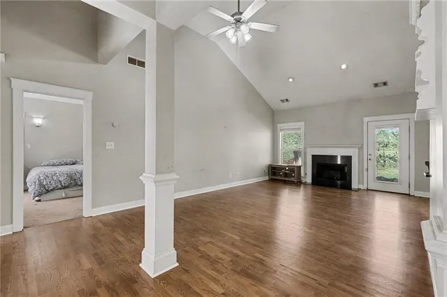 an empty room with wooden floor fireplace and windows