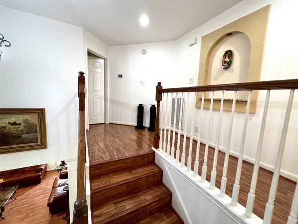 a view of a hallway with wooden floor and staircase