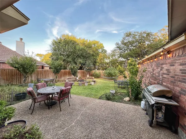 a patio with table and chairs with plants and wooden floor