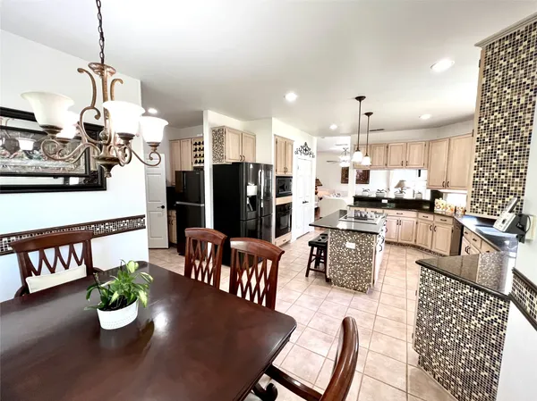 a kitchen with stainless steel appliances kitchen island granite countertop a dining table chairs and a living room