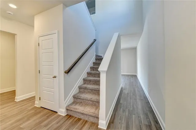 a view of staircase with wooden floor and white walls