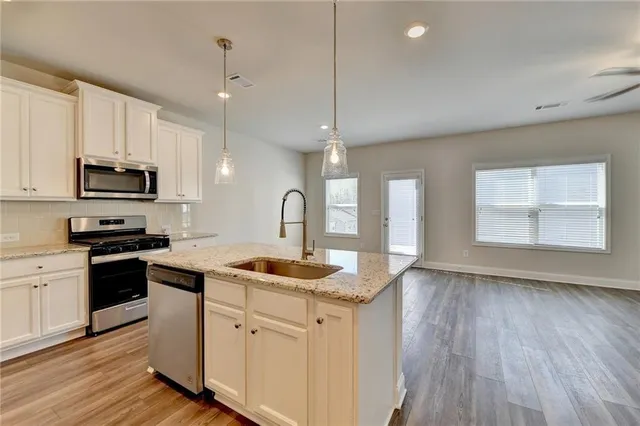 a kitchen with stainless steel appliances granite countertop a sink a stove and a wooden floors