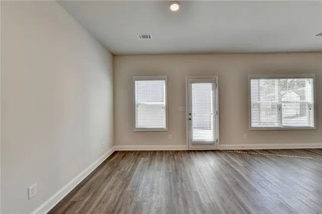 an empty room with wooden floor and windows
