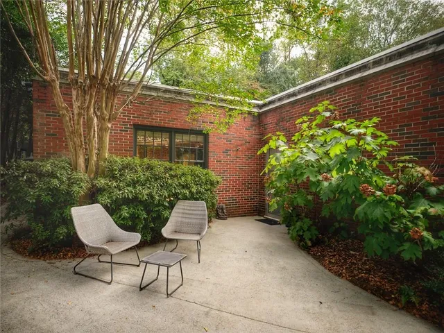 a backyard of a house with table and chairs and potted plants