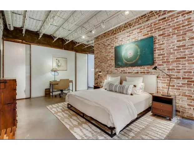 a bedroom with a bed a mirror on dresser and a flat screen tv