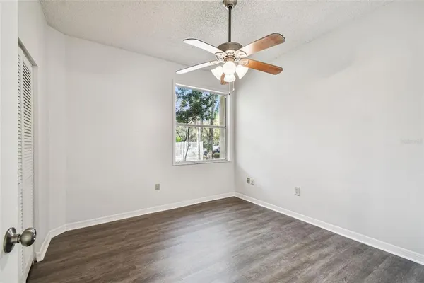 an empty room with wooden floor fan and windows