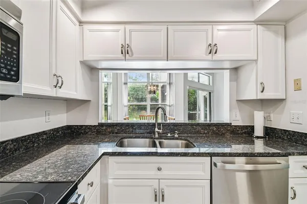 a kitchen with stainless steel appliances granite countertop a sink and cabinets with wooden floor