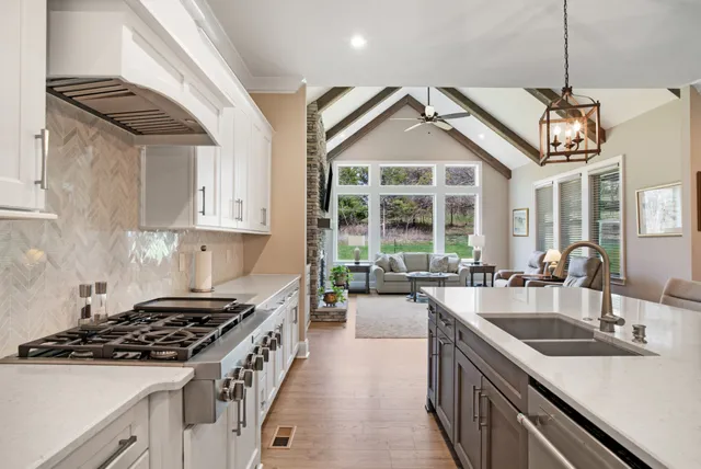 a kitchen with stainless steel appliances granite countertop a dining table chairs refrigerator and cabinets