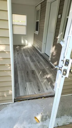 a view of an empty room with wooden floor and a window