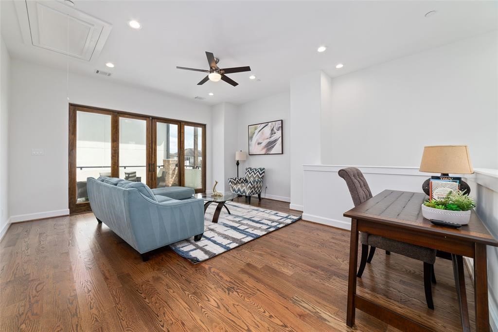 710 Delano Street, Unit A Houston, TX 77003 - Photo 23 of 32 This photo showcases a bright, open living space with hardwood floors, modern ceiling fan, and ample natural light from large glass doors.