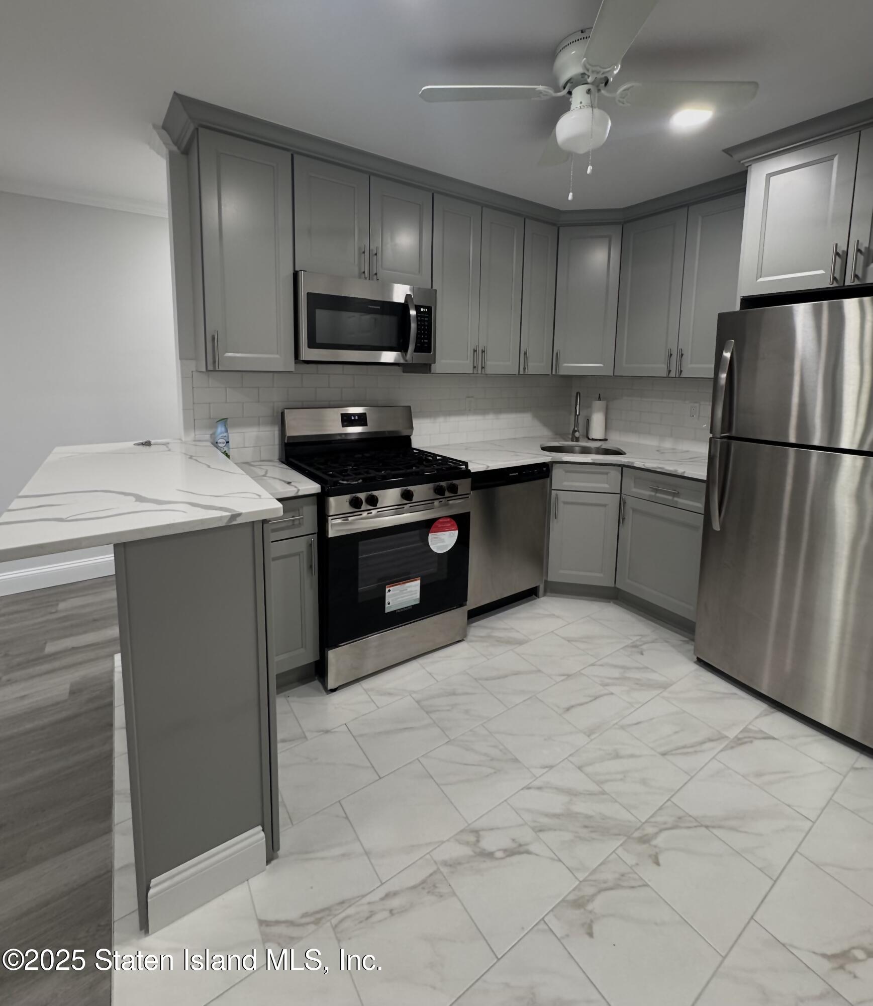 170 Devon Loop, Unit 2 Staten Island, NY 10314 - Photo 2 of 9 a kitchen with stainless steel appliances granite countertop a sink a stove a refrigerator and cabinets