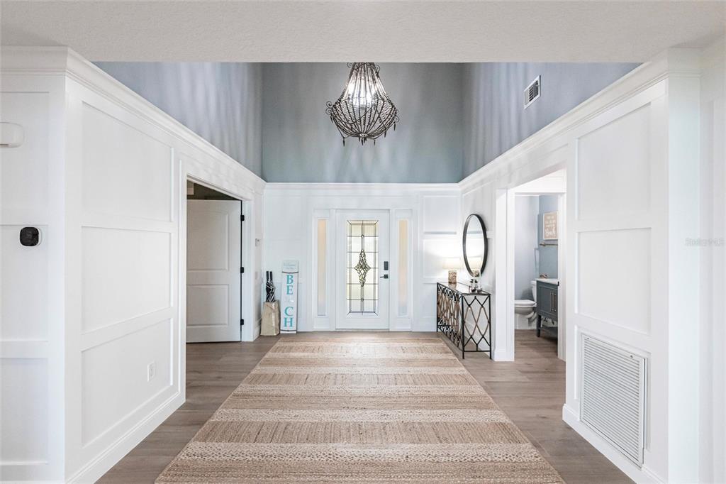 8115 Manasota Key Road Englewood, FL 34223 - Photo 18 of 67 a view of a hallway to a livingroom with wooden floor and a chandelier
