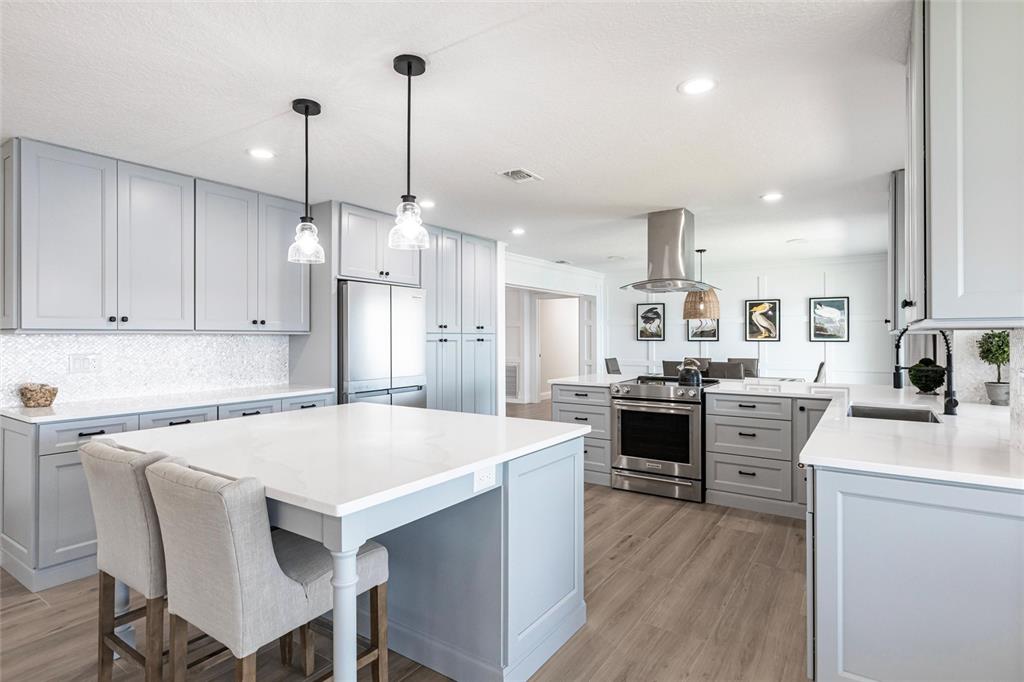 8115 Manasota Key Road Englewood, FL 34223 - Photo 26 of 67 a kitchen with a stove a sink a kitchen island with chairs and wooden floor