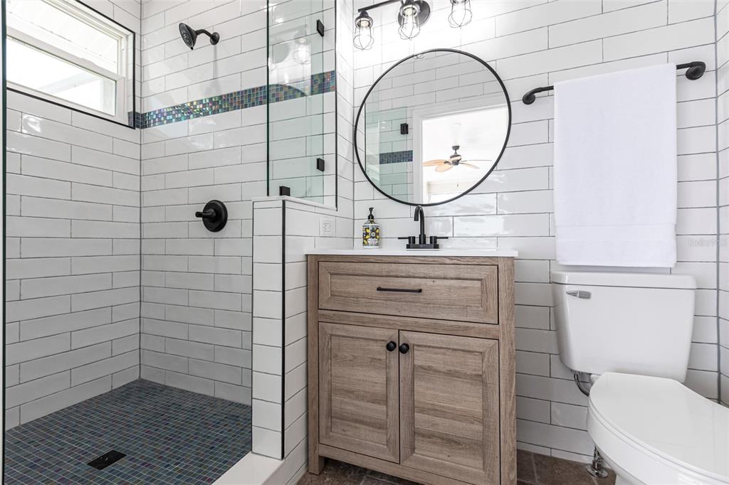 8115 Manasota Key Road Englewood, FL 34223 - Photo 61 of 67 a bathroom with a sink a mirror a toilet and a shower