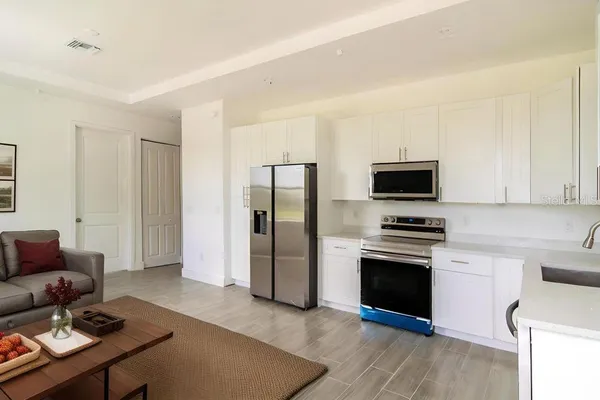 a kitchen with stainless steel appliances a stove a refrigerator a sink a stove with white cabinets