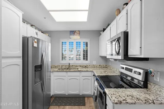 a kitchen with stainless steel appliances granite countertop a refrigerator sink and stove