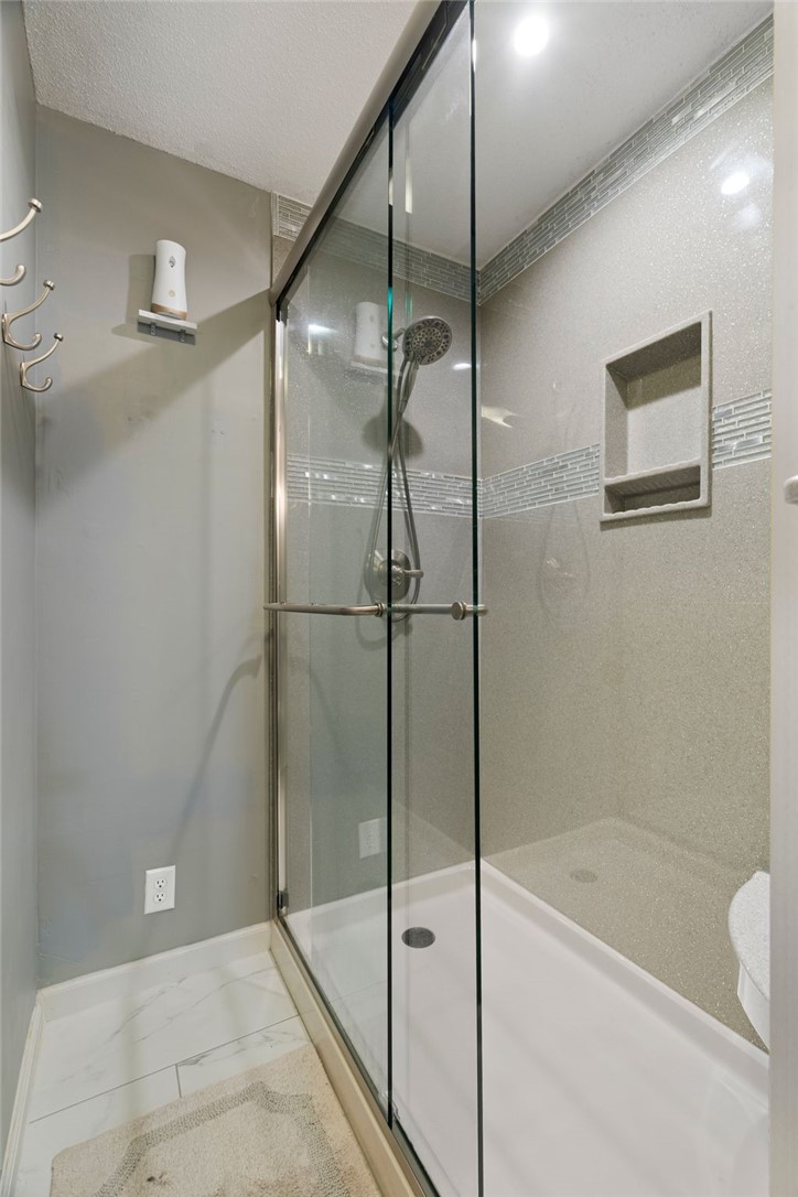 624 Locke Street Alma, AR 72921 - Photo 14 of 32 Glass-enclosed shower featuring a handheld showerhead, a built-in shower niche, and mosaic tile accents