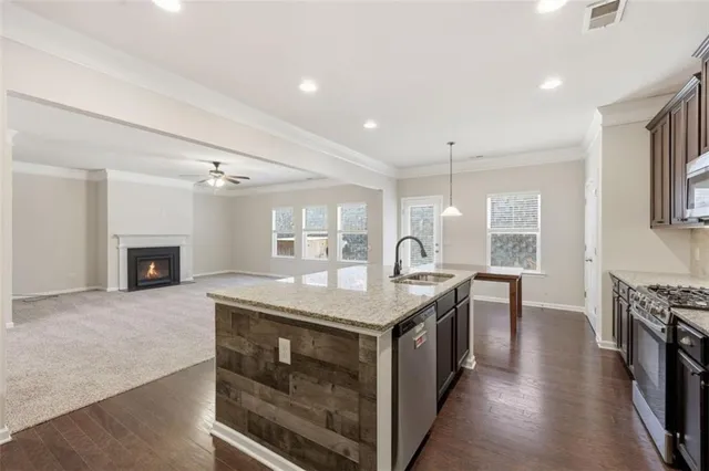 a kitchen with stainless steel appliances granite countertop wooden cabinets a stove top oven a sink and dishwasher