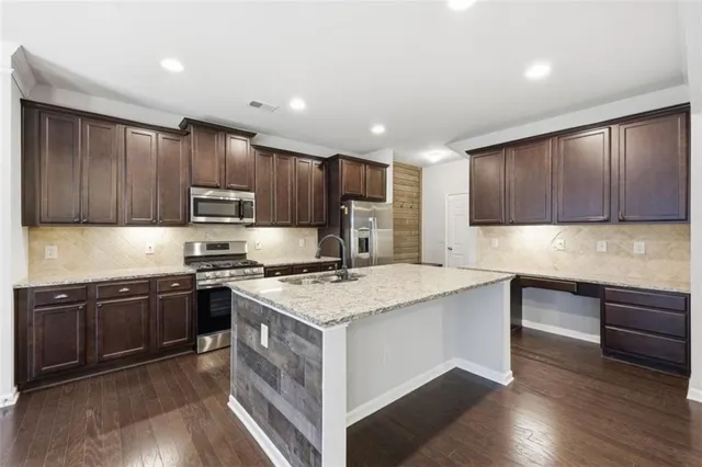 a large kitchen with kitchen island a sink stainless steel appliances and a fireplace
