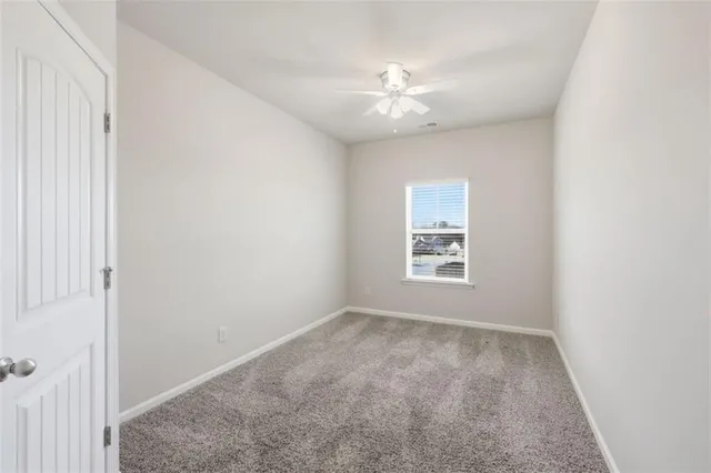 an empty room with a ceiling fan and window