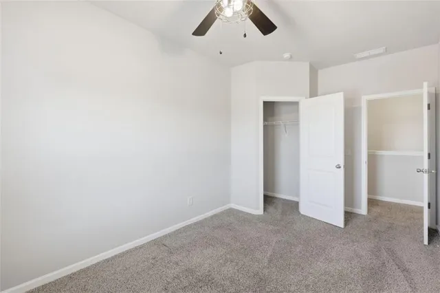 an empty room with a chandelier fan and windows
