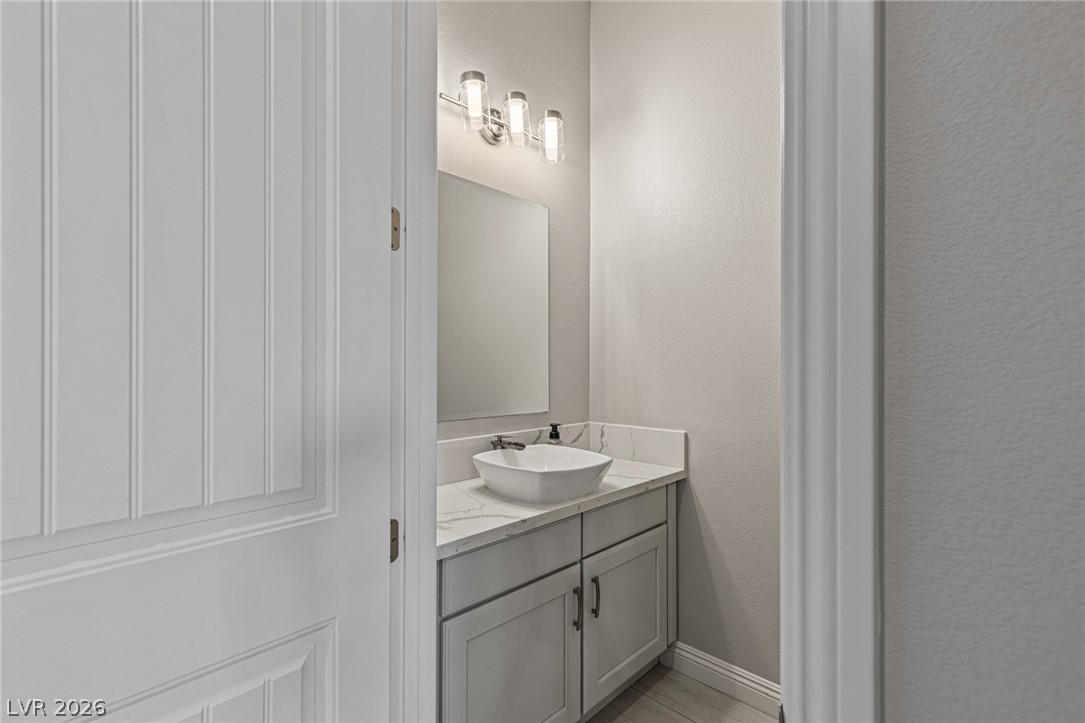 7036 Arabian Ridge Street Las Vegas, NV 89131 - Photo 14 of 64 A well-appointed powder room features a contemporary vessel sink set above a quartz countertop.