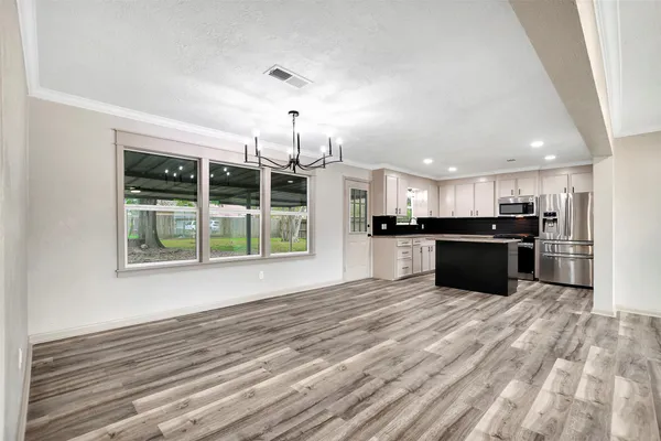 a view of an empty room with a window and kitchen view