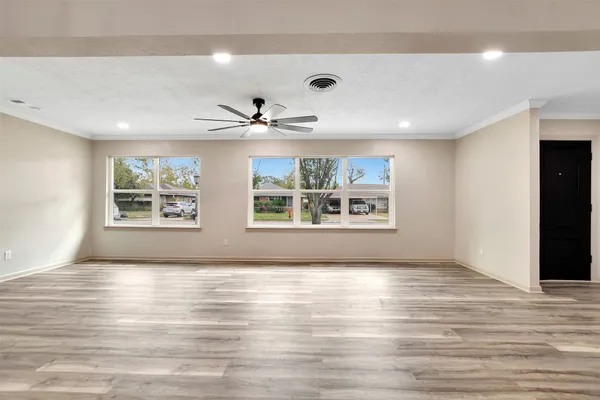 a view of an empty room with a window and wooden floor