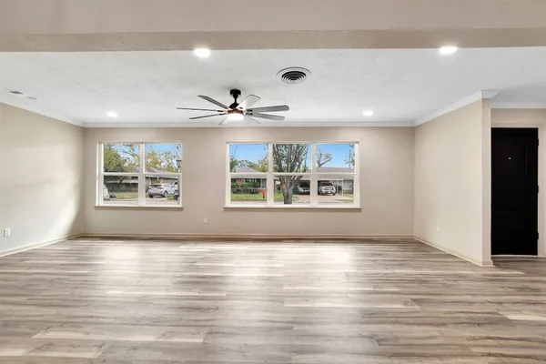 a view of an empty room with a window and wooden floor
