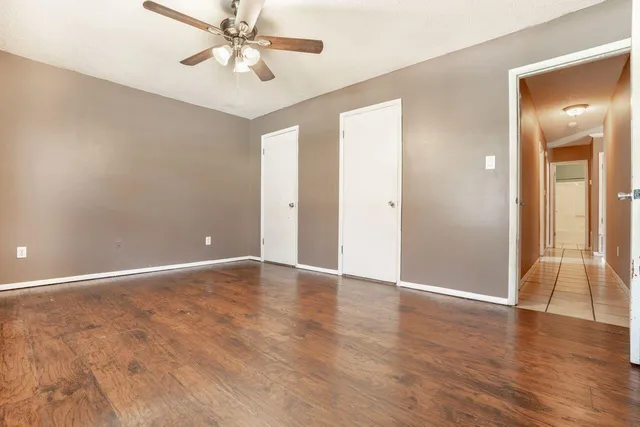an empty room with wooden floor and a ceiling fan