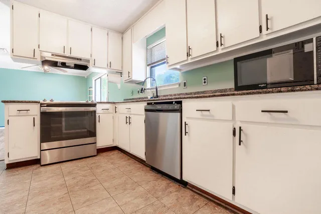 a kitchen with stainless steel appliances granite countertop a stove microwave and cabinets