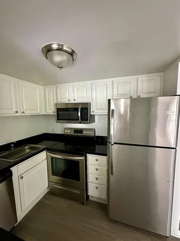 a kitchen with stainless steel appliances granite countertop a refrigerator a stove a microwave and cabinets