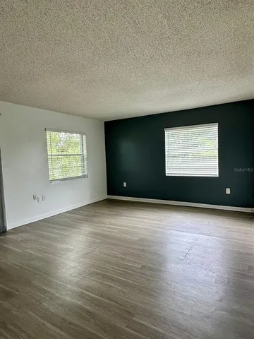 a view of an empty room with wooden floor and windows