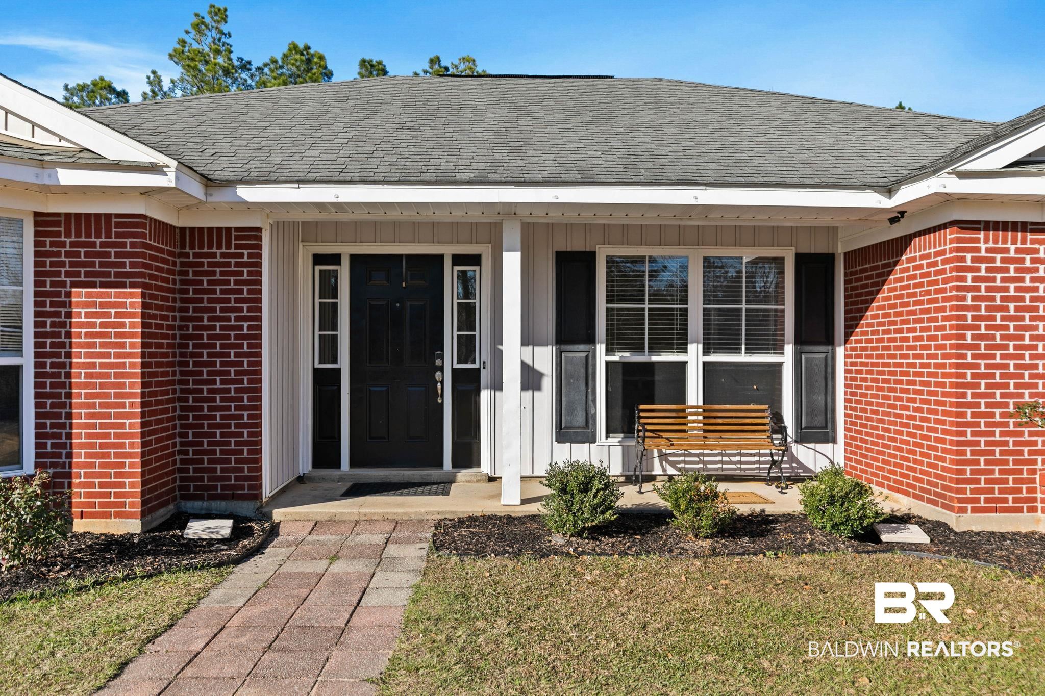 55750 Lottie Road Perdido, AL 36562 - Photo 75 of 84 Doorway to property with brick siding, a lawn, a shingled roof, and covered porch