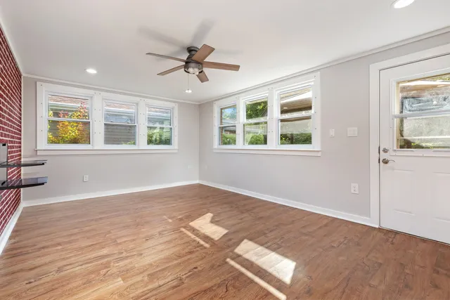 a view of an empty room with a window and wooden floor