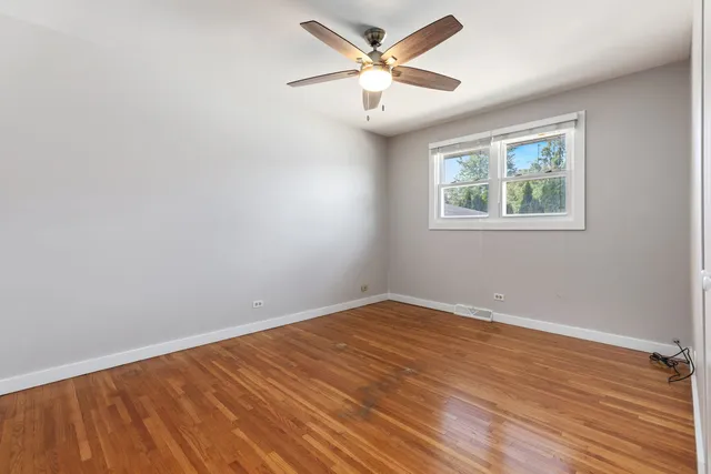 an empty room with wooden floor and ceiling fan
