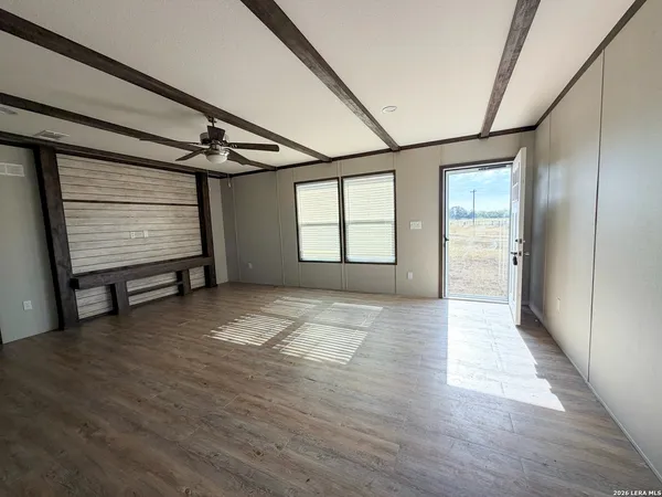 a view of an empty room with a window and wooden floor