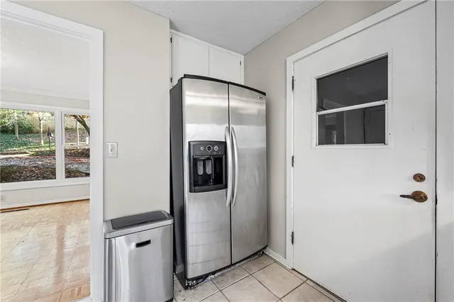 a view of a refrigerator in kitchen and an empty room
