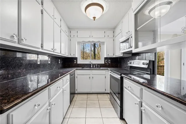 a kitchen with stainless steel appliances granite countertop a stove a sink and a microwave