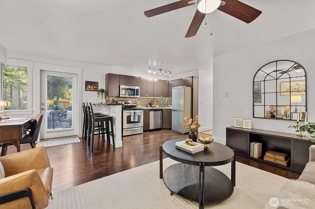 a living room with stainless steel appliances kitchen island a table and chairs in it